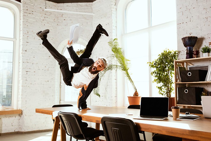 Business Insurance - Businessman Having Fun Break Dancing on a Table in His Office